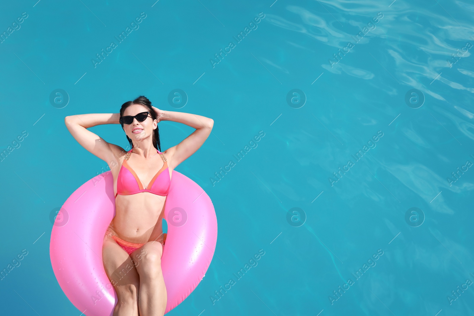 Photo of Beautiful young woman in bikini swimming with inflatable ring, above view. Space for text