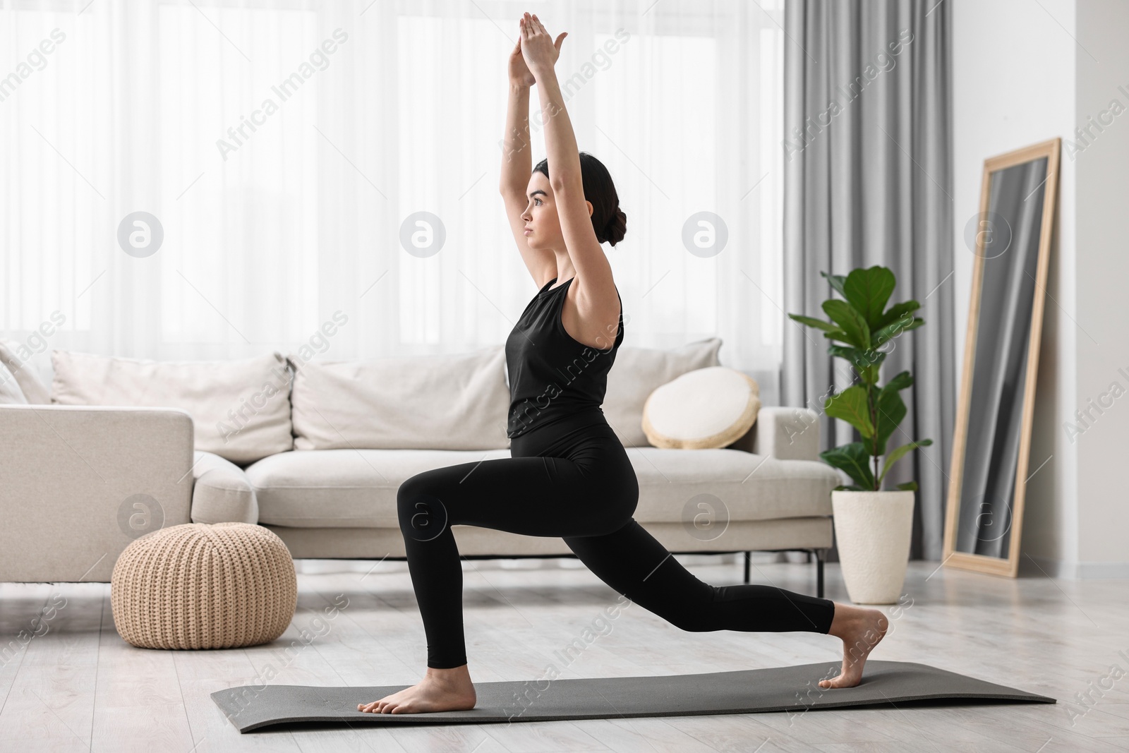 Photo of Girl practicing crescent asana on yoga mat at home. High lunge pose