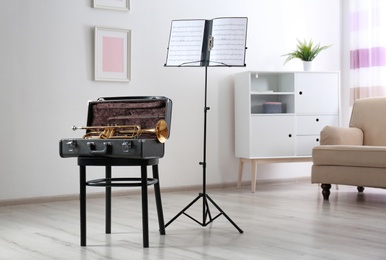 Photo of Trumpet, case and note stand with music sheets in room