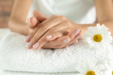 Photo of Woman with smooth hands and flowers on towel, closeup. Spa treatment