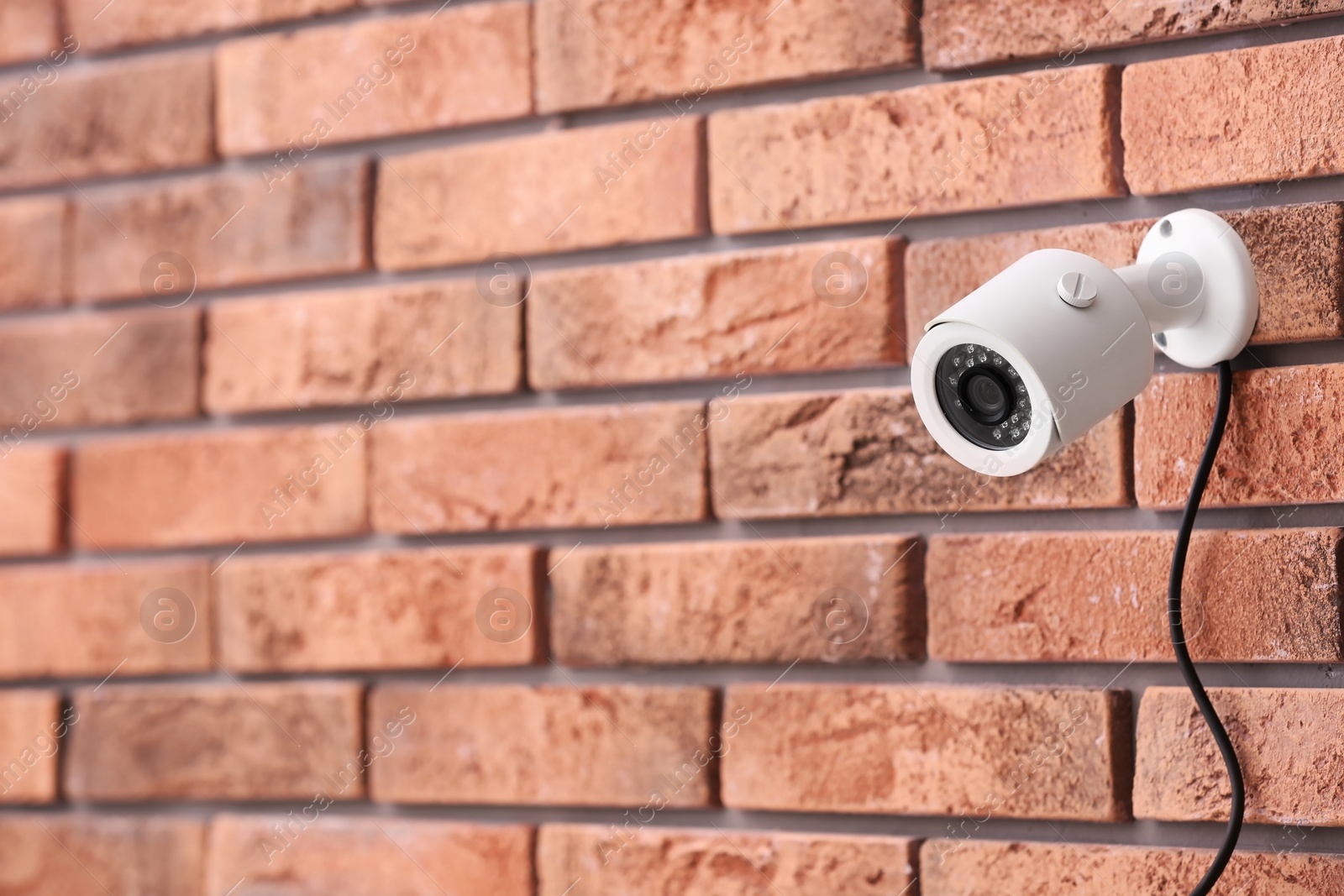 Photo of Modern security CCTV camera on brick wall