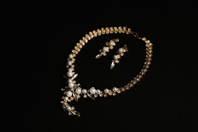 Photo of Set of elegant necklace and earrings on black background. Luxury jewelry