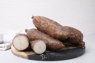 Whole and cut cassava roots on white table