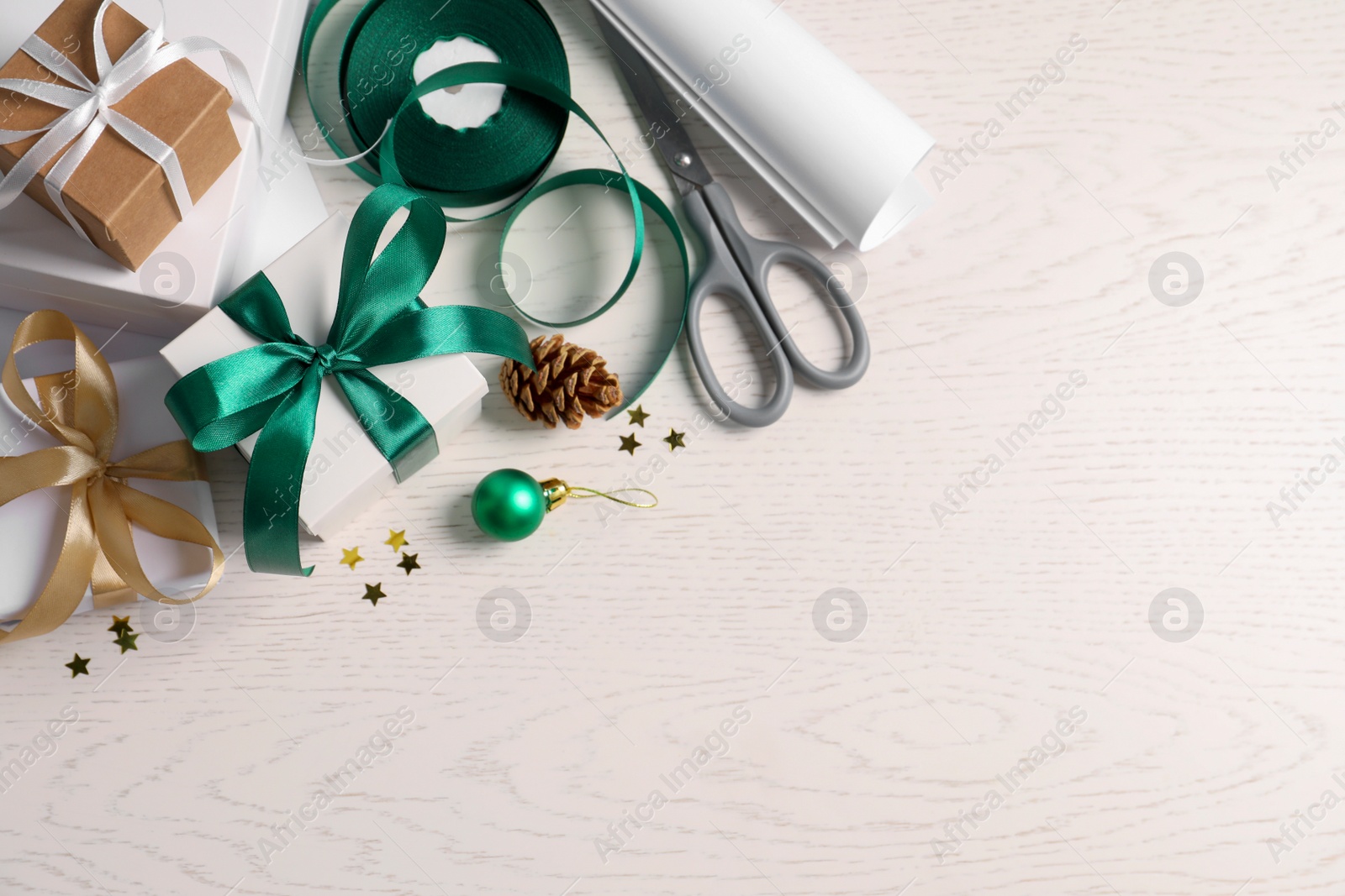 Photo of Flat lay composition with beautiful gift boxes and Christmas decorations on white wooden table. Space for text