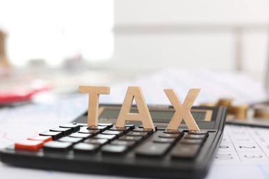 Word TAX and calculator on table, closeup