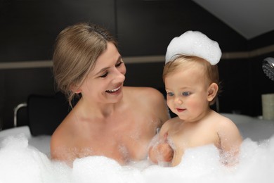 Photo of Mother with her child taking bubble bath together indoors