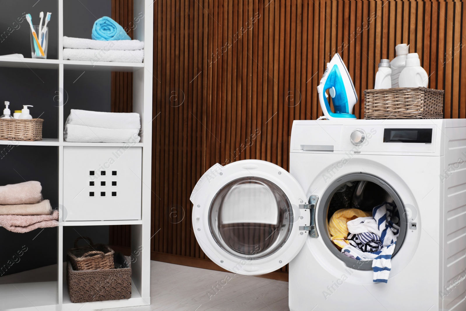 Photo of Laundry room interior with washing machine near wooden wall