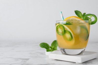 Spicy cocktail with jalapeno, lemon and mint on white marble table. Space for text