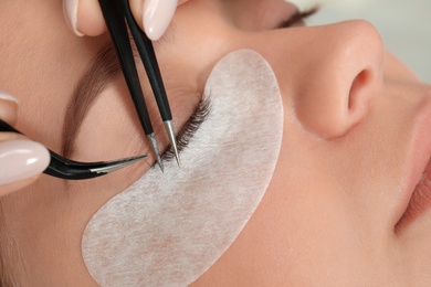 Young woman undergoing eyelash extension procedure, closeup