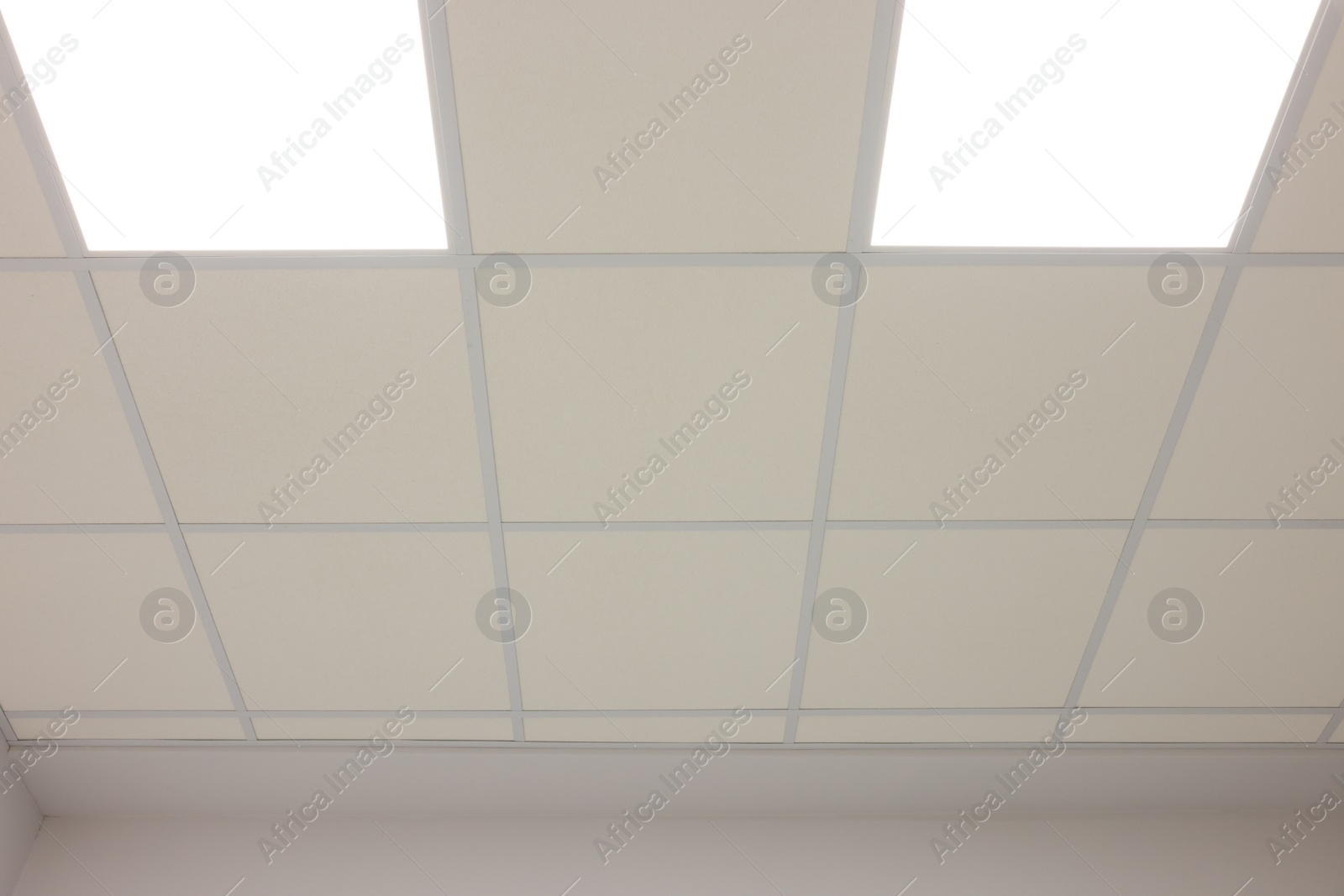 Photo of White ceiling with PVC tiles and lighting indoors, low angle view