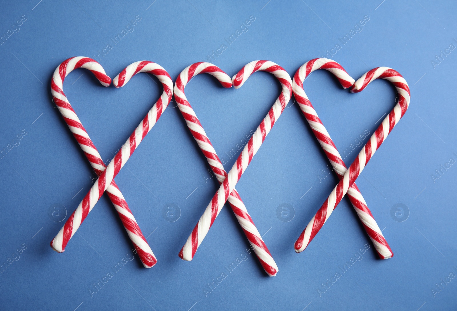 Photo of Candy canes on blue background, flat lay