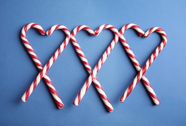 Photo of Candy canes on blue background, flat lay