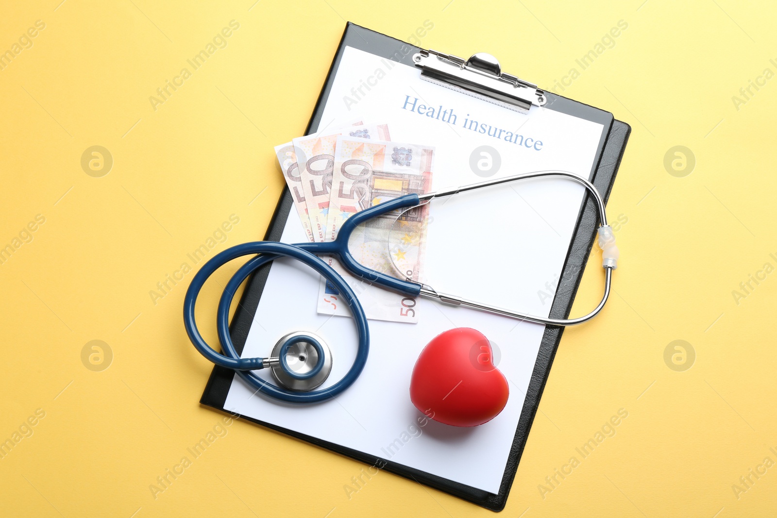 Photo of Flat lay composition with medical insurance form, money, heart and stethoscope on yellow background