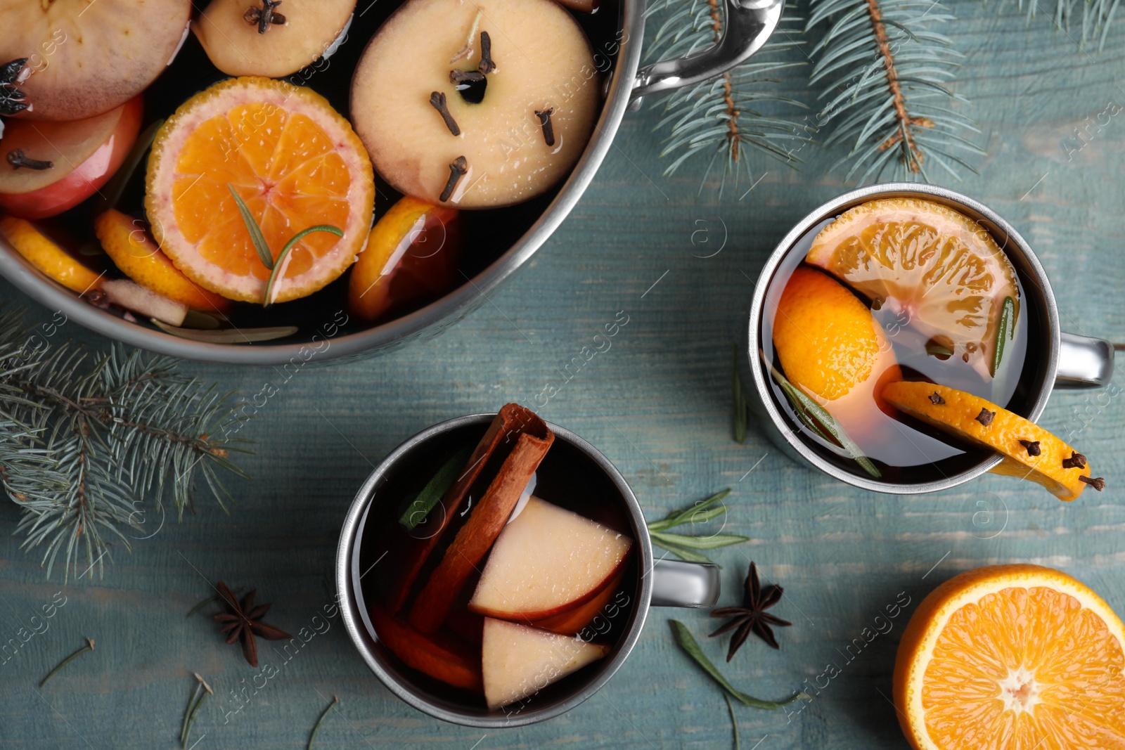 Photo of Tasty mulled wine with spices on blue wooden table, flat lay