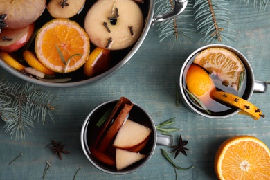 Photo of Tasty mulled wine with spices on blue wooden table, flat lay