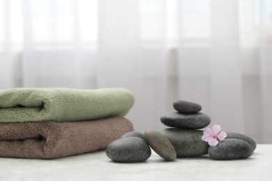 Photo of Spa stones, fresia flower and towels on white table indoors