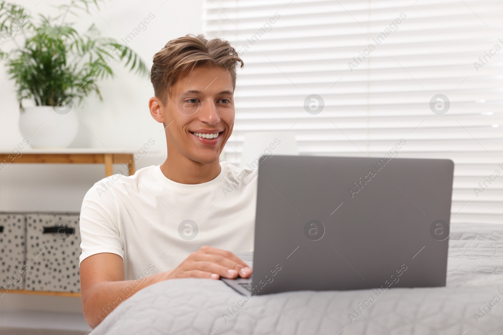 Photo of Happy young man having video chat via laptop indoors