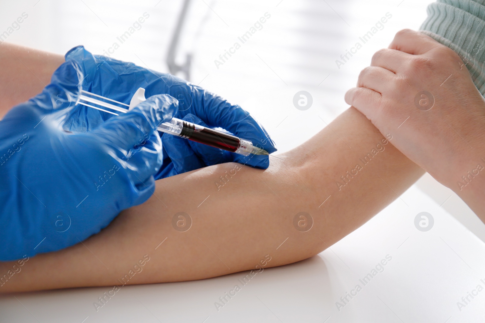 Photo of Nurse drawing blood sample from patient in clinic, closeup