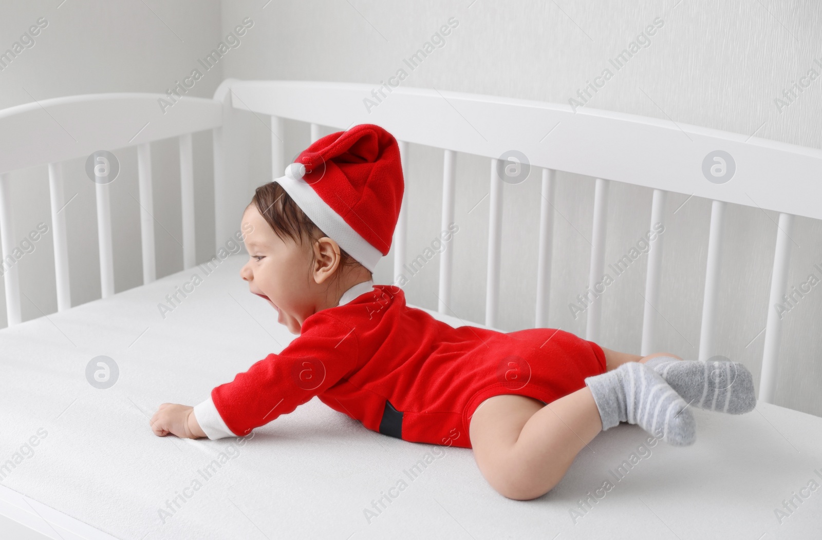 Photo of Cute baby wearing festive Christmas costume in crib