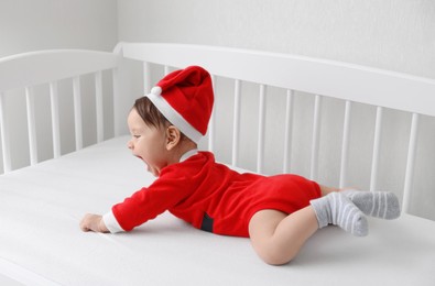 Cute baby wearing festive Christmas costume in crib