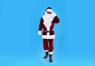 Photo of Full length portrait of Santa Claus with sunglasses on light blue background