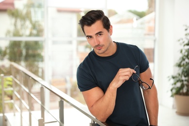 Portrait of handsome young man leaning on railing indoors