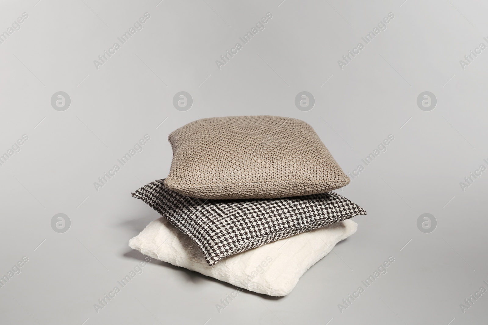 Photo of Stylish decorative pillows stacked on light background