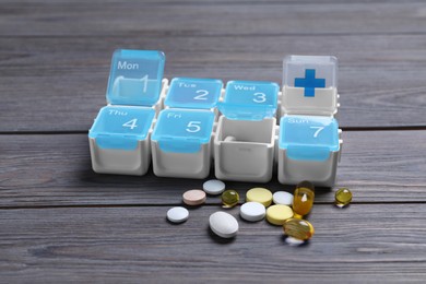 Weekly pill box with medicaments on wooden table
