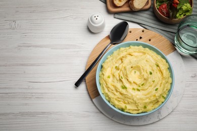 Photo of Bowltasty mashed potatoes with greens served on white wooden table, flat lay. Space for text