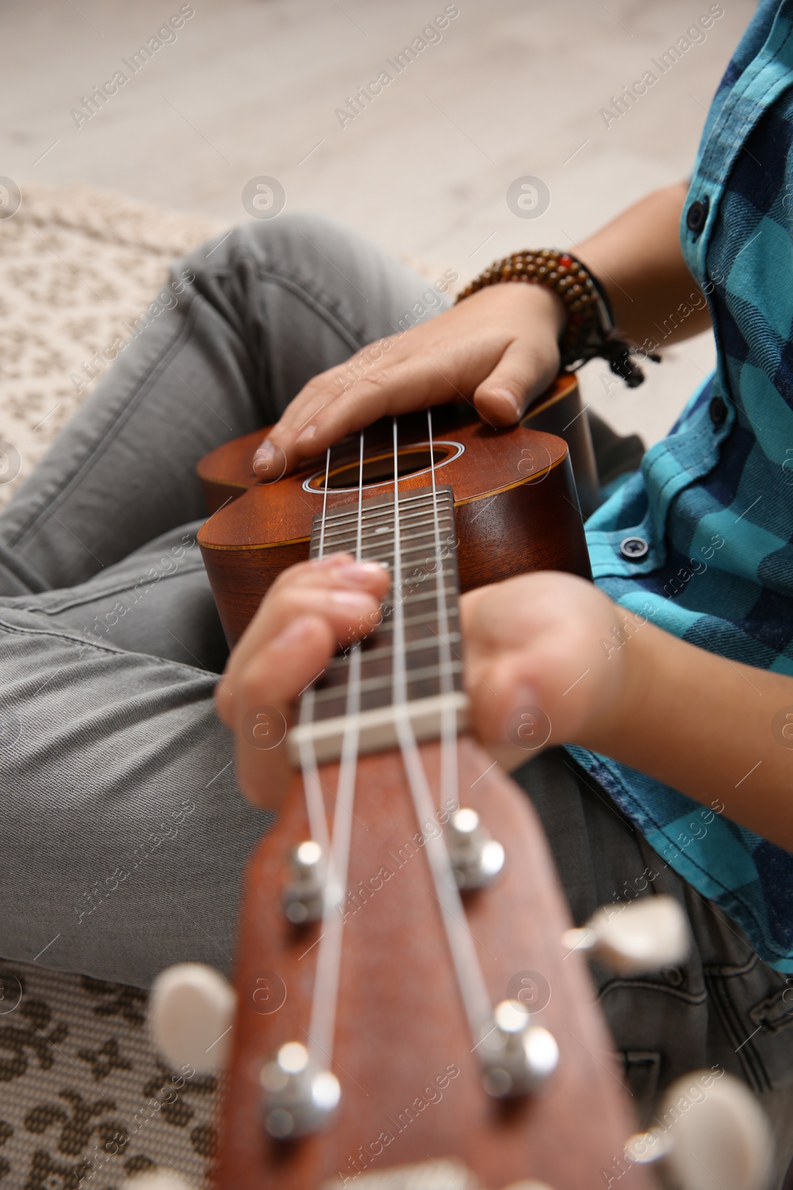 Photo of Little boy playing guitar on floor, closeup