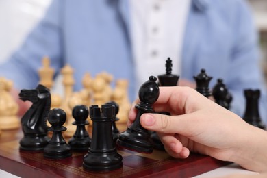 Photo of Little child playing chess with father indoors, closeup