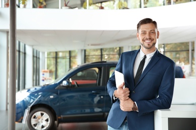 Salesman with tablet in modern car dealership