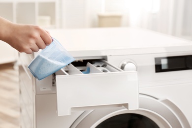 Photo of Woman pouring powder into drawer of washing machine indoors, closeup. Laundry day