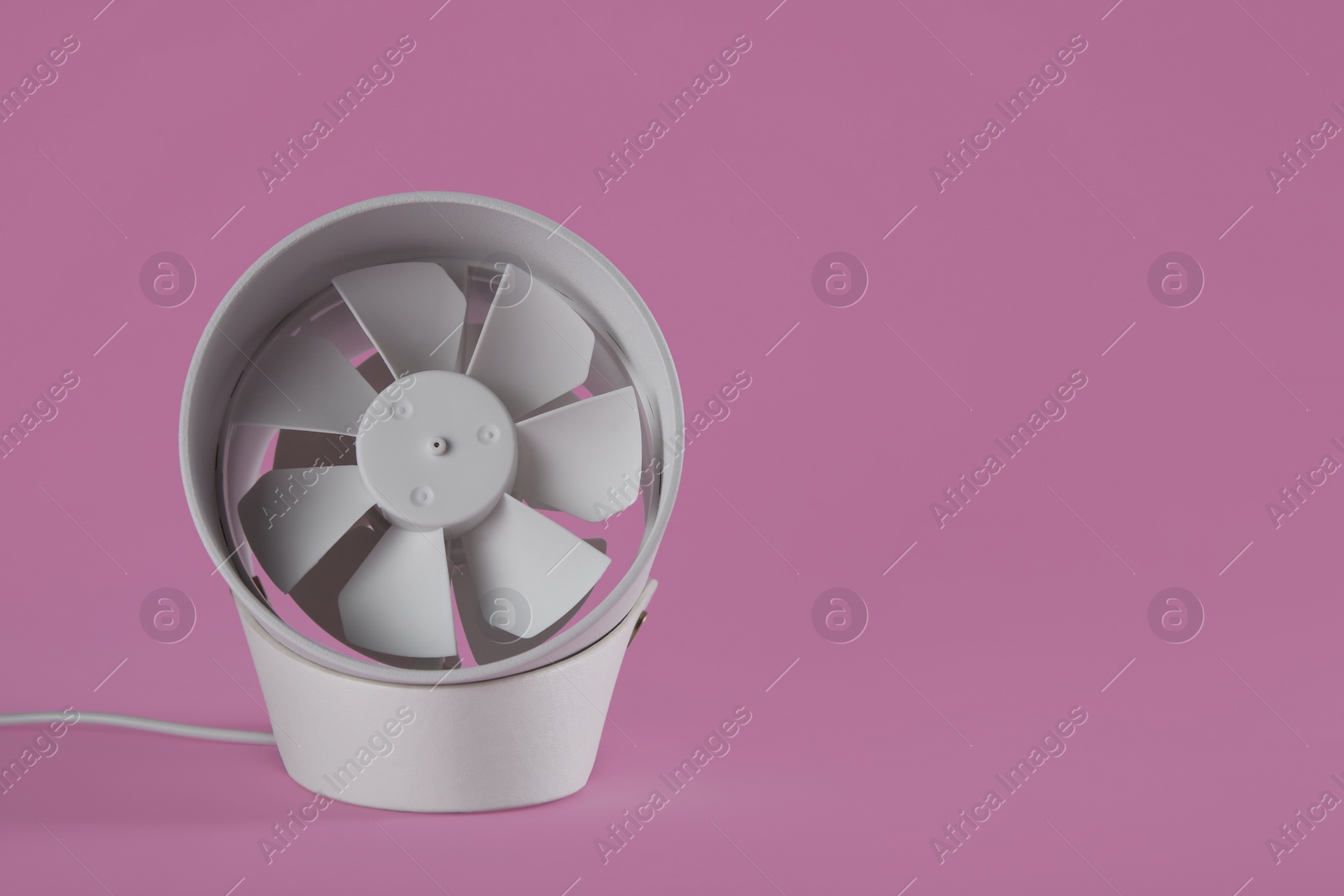 Photo of Modern electric fan on pink background. Space for text