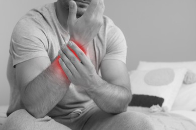 Man suffering from rheumatism at home, closeup. Black and white effect with red accent in painful area