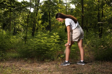 Woman applying insect repellent on leg in park. Tick bites prevention