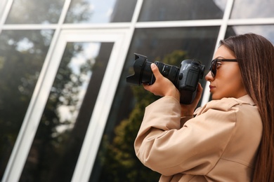 Private detective with camera spying near building on city street