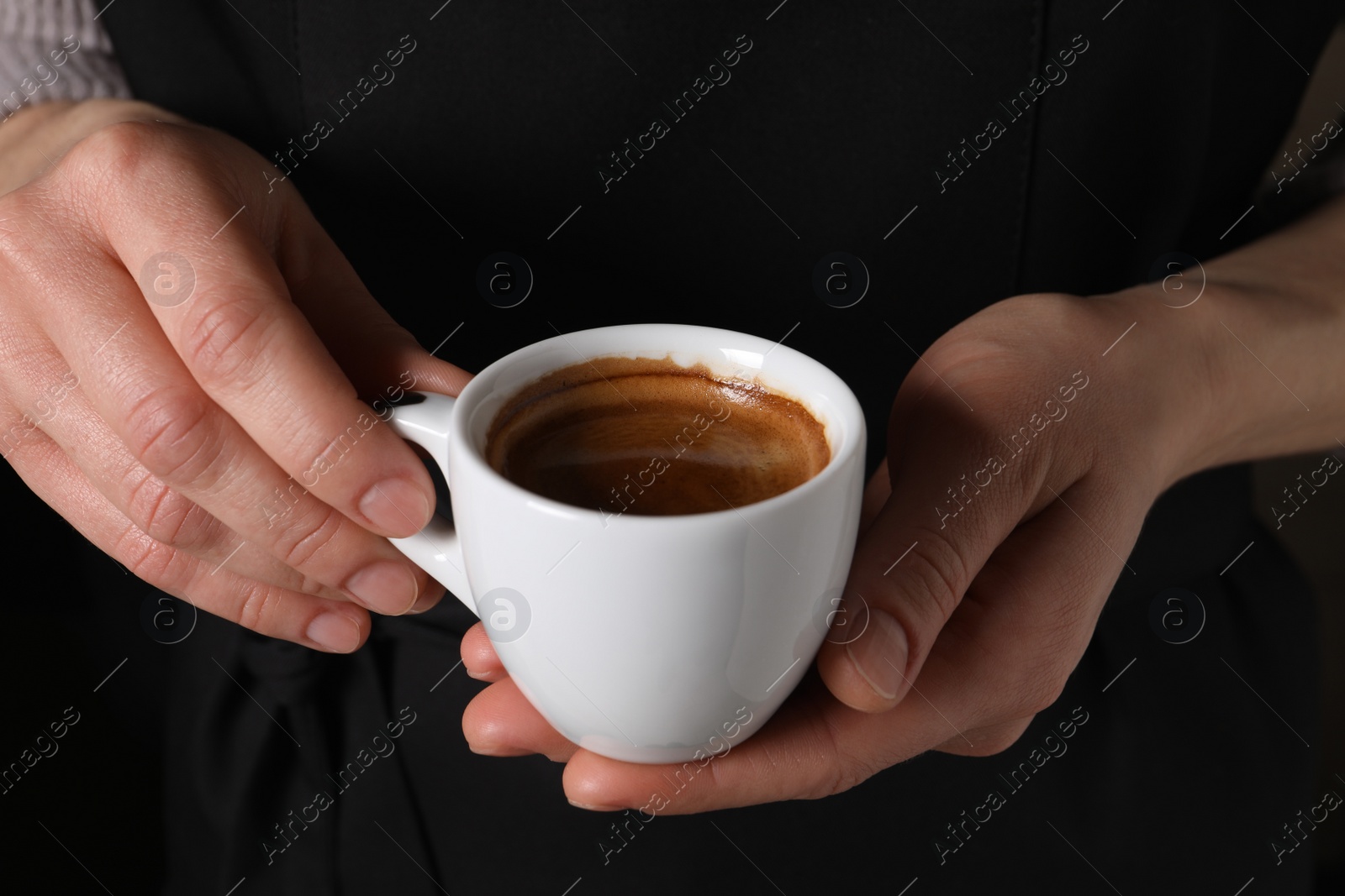 Photo of Woman holding cup of fresh aromatic espresso, closeup