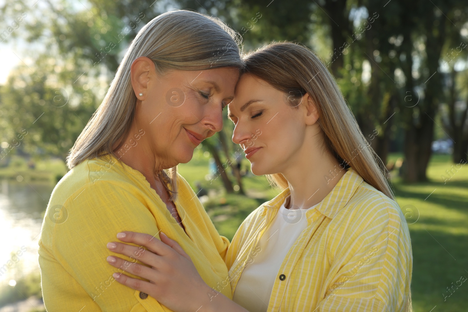 Photo of Family portrait of happy mother and daughter spending time together in park on sunny day