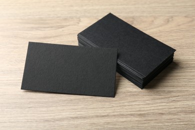 Photo of Blank black business cards on wooden table. Mockup for design
