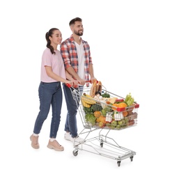 Happy couple with shopping cart full of groceries on white background