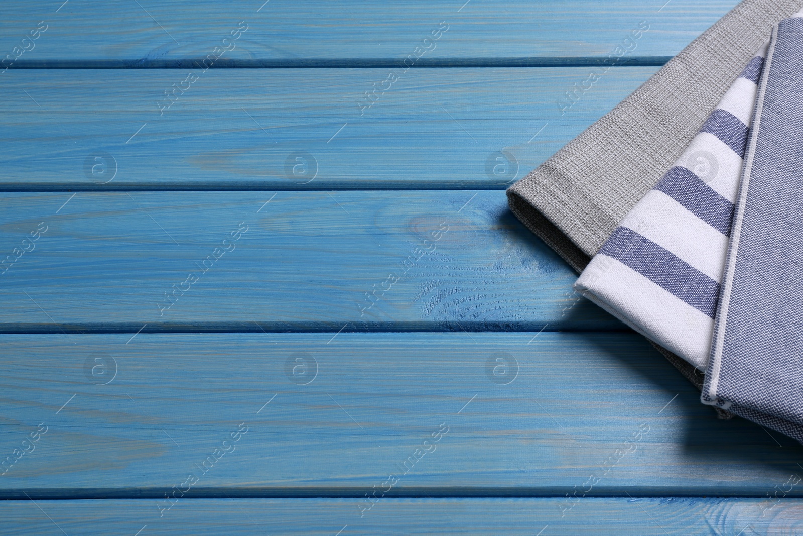 Photo of Different kitchen towels on blue wooden table. Space for text