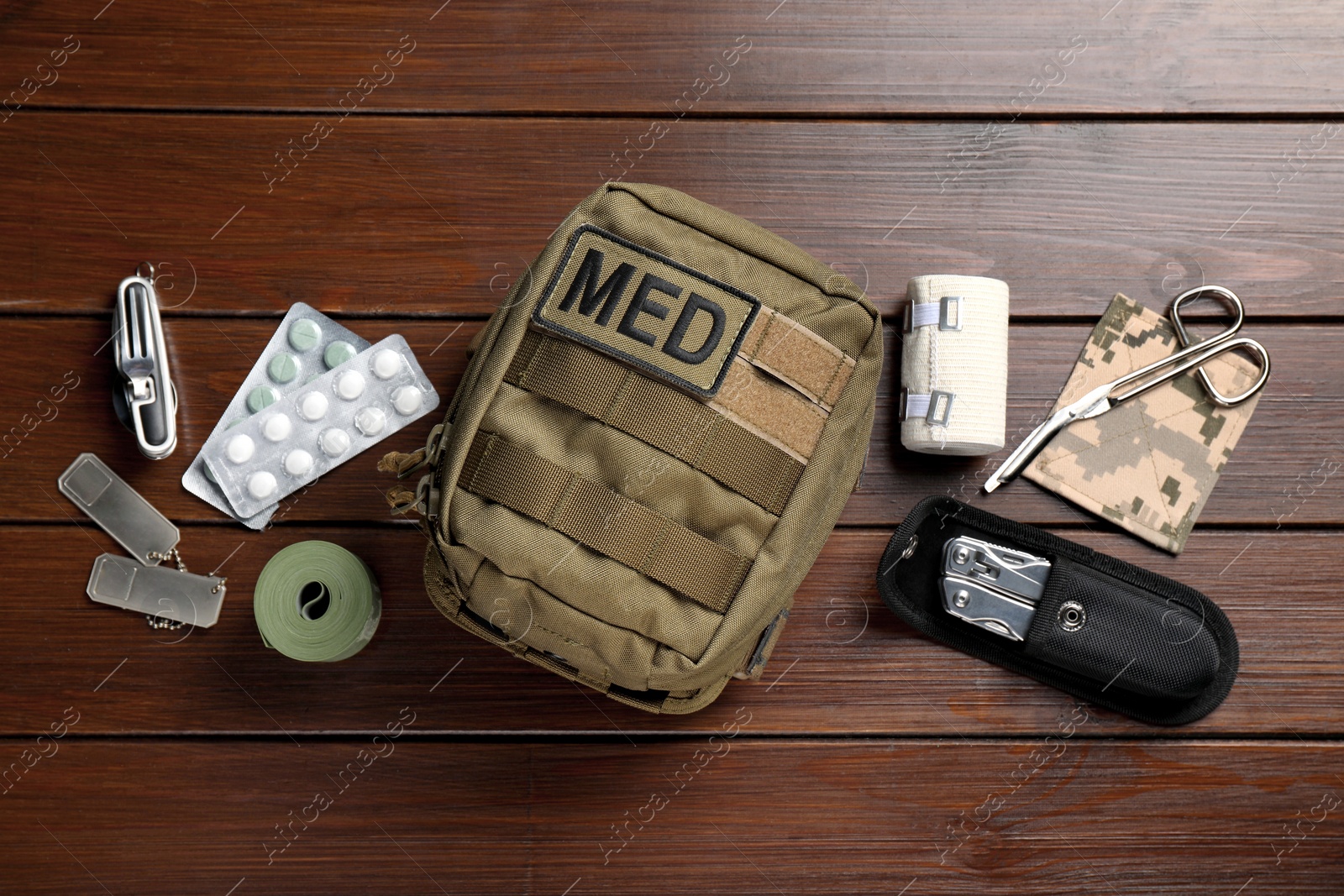 Photo of Military first aid kit on wooden table, flat lay