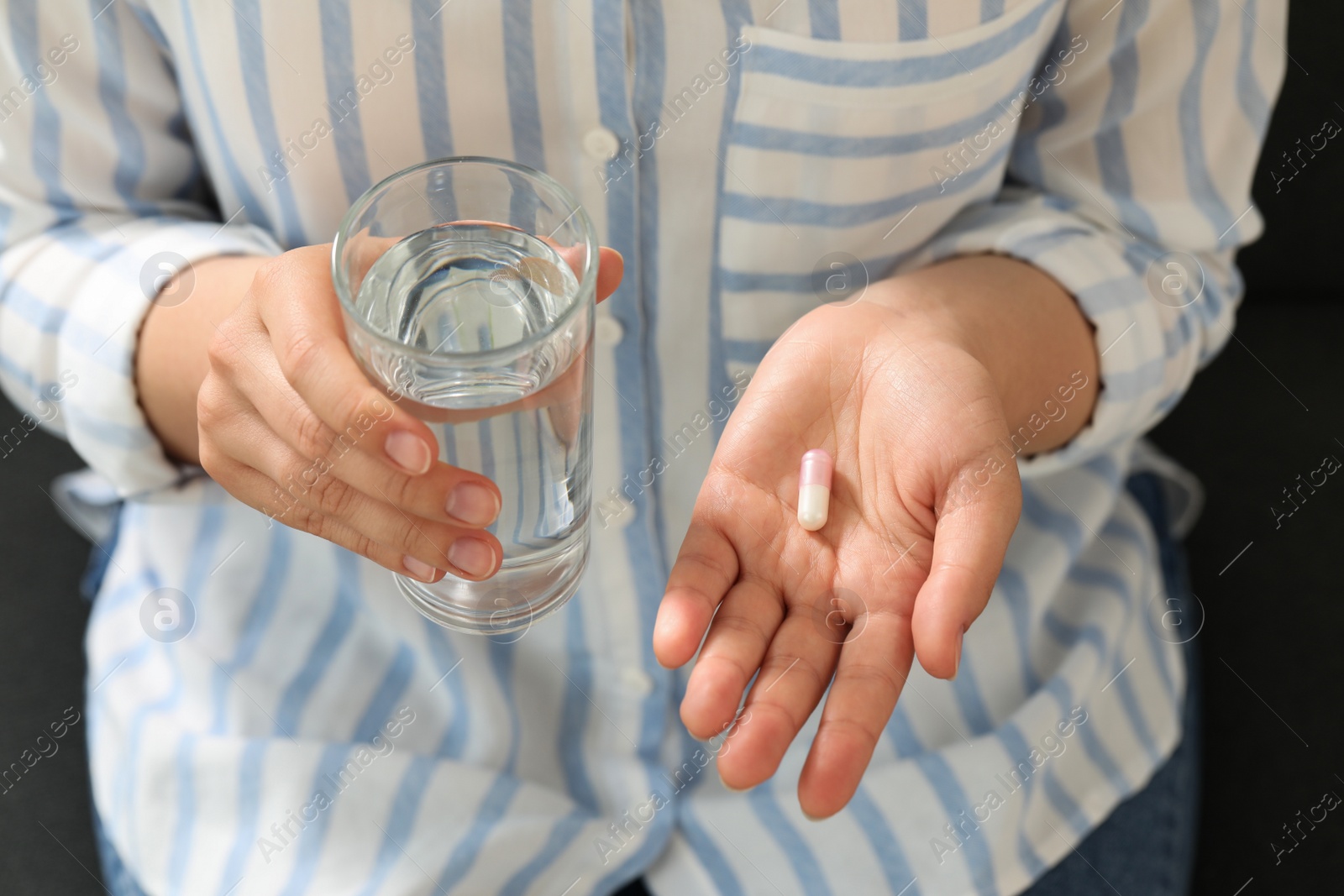 Photo of Young woman with dietary supplement pill and glass of water, above view