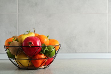 Photo of Metal basket with different ripe fruits on grey table. Space for text