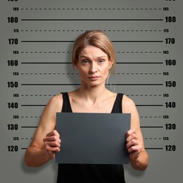 Image of Criminal mugshot. Arrested woman with blank card against height chart
