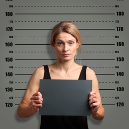 Criminal mugshot. Arrested woman with blank card against height chart