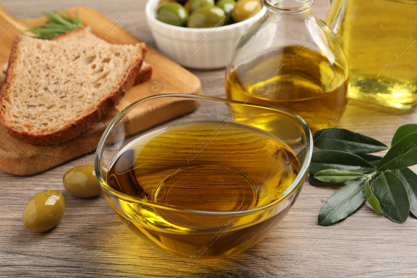 Photo of Fresh oil, ripe olives and green leaves on wooden table