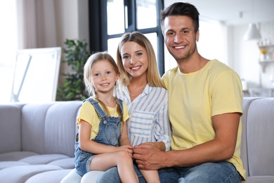 Happy family with little daughter on sofa in living room