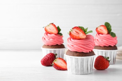 Sweet cupcakes with fresh strawberries on white table. Space for text